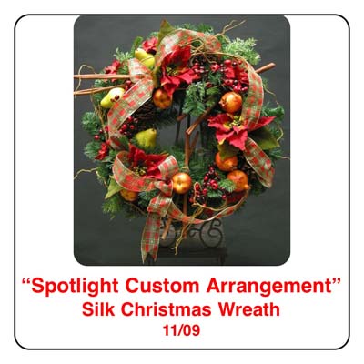 November Spotlight Christmas Wreath Arrangement using cinammon sticks, plaid ribbon, pears, apples, pomegrantes, artificial berries, christmas pine, pinecones, and cedar